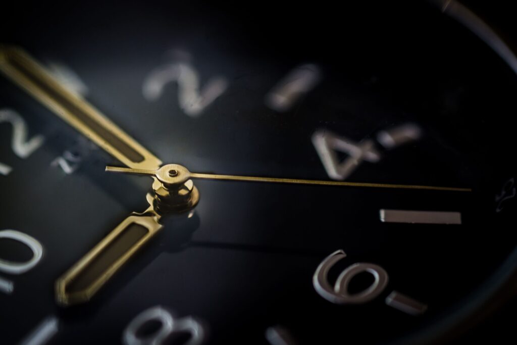 Detailed macro shot of an analog wristwatch showing gold hands and blurred numerals.
